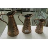 A set of 3 graduated copper jugs.