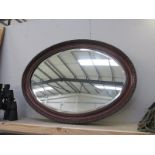 An oval wooden framed mirror