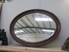 An oval wooden framed mirror