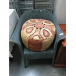 A Lloyd Loom chair and leather pouffe