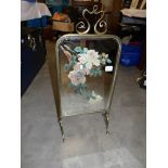 A brass framed fire screen with painted mirrored centre.