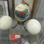 A decorated ostrich egg and 2 undecorated ostrich eggs.