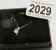A diamond pendant in a cluster style in white gold with attached white gold chain.