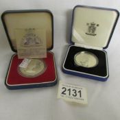 A mint silver proof Prince of Wales £5 coin and a mint silver Guernsey royal visit coin.