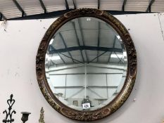 An oval bevel edged mirror in ornate frame.