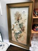 A gilt framed painting of flowers on opaque glass.