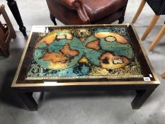 A brass and wood coffee table with world map in top.