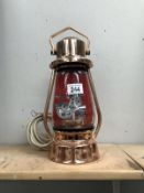 An unusual table lamp in the shape of a hurricane lamp with inset traction engine.