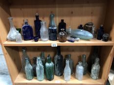 2 shelves of coloured glass bottles including old school milk bottles.