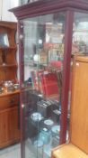 A tall display cabinet with mirror back and 4 glass shelves