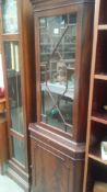 A darkwood stained corner cupboard with astragal glazed door