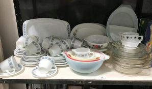 A shelf of 1970's Pyrex dinnerware and a shelf of plated cutlery etc.