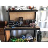A metal framed work bench with backboard for tool hooks and an overhead shelf