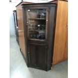 A glazed oak corner cabinet