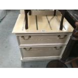 A 2 drawer chest of drawers with brass suitcase straps on top