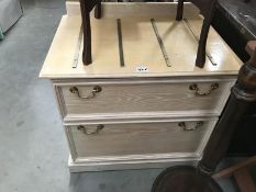 A 2 drawer chest of drawers with brass suitcase straps on top