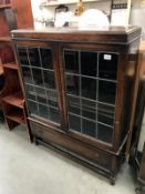 A 1930's oak display cabinet with leaded glass doors & drawer