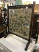 An oak fire screen with embroidered panel.