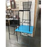A metal folding table and a pair of metal mesh bar stools