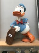 A large Donald duck with suitcase statue