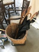 A wicker trolley/basket and quantity of walking sticks and umbrellas