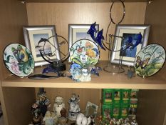 A shelf of miscellaneous. including. animal pictures, butterfly plates, dolphins etc.