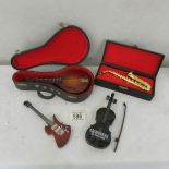 A cased miniature saxaphone, a cased miniature mandolin,