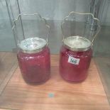 2 cranberry glass biscuit barrels with plated rims and lids.