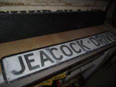 A pressed aluminium 'Peacock Drive' street sign.