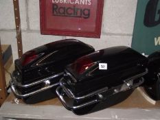 A pair of motorcycle pannier boxes with fittings.