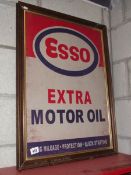 A retro Esso Extra Motor Oil metal sign in an old wooden frame.