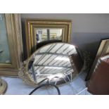 An ornate small oval mirror and framed bevel edge mirror