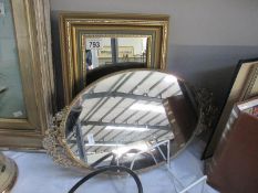 An ornate small oval mirror and framed bevel edge mirror