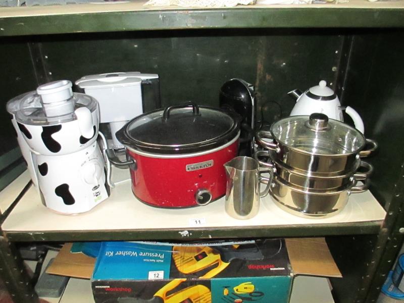 A shelf of kitchen items including a crock pot, electric can opener kettle etc.