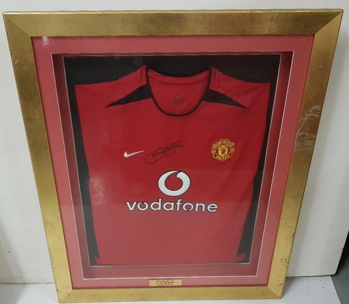 A Manchester United (Vodafone) Jersey, signed “David Beckham”, dated 2002/2003, in a gilt frame (