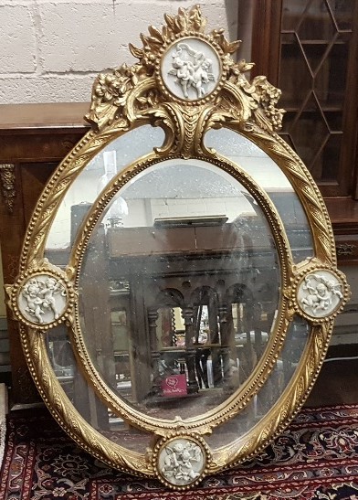 Elaborately Carved Oval Shaped Wall Mirror, featuring 4 round cherub plaques with double borders,