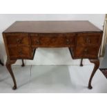 A figured walnut serpentine front writing table, fitted with 4 small and 1 long drawer, on shell