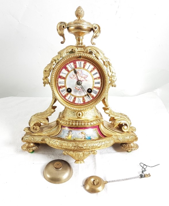 Ornate gilt metal Mantel Clock with porcelain painted face and central panel featuring cherubs,