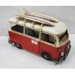 Tin model of a vintage Camper Van (carrying 2 surf boards) painted red and cream, 43cm w x 22cm h