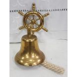 Ornamental brass ships bell, 18cm H, on a wheel shaped wall bracket.