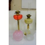 2 Brass Columned Oil Lamps/ 1 with red glass bowl & globe shaped pink shade. 1 with cream bowl and