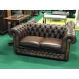 A pair of brown leather deep buttoned chesterfield settees 62"W