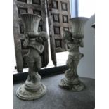 A pair of Regency cast iron figures of semi nude boys holding aloft a ribbed design urn 18" W x 38"