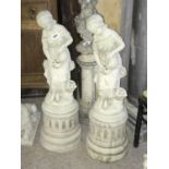 Pair of stone sculptures of seated women on plinths 36" H