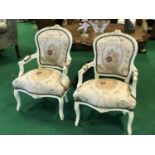 A pair of painted chairs with floral design upholstery