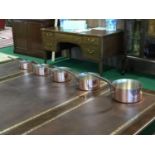 A set of graduated copper saucepans