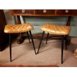 Two tanned leather and metal stools with four out swept legs. (