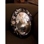 Oval ebonised bevelled edged mirror decorated with flowers. ( 47 cm w x 57 cm H).