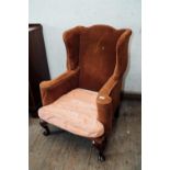 Pair of leather upholstered wing backed chair raised on mahogany legs in the Georgian manner. {
