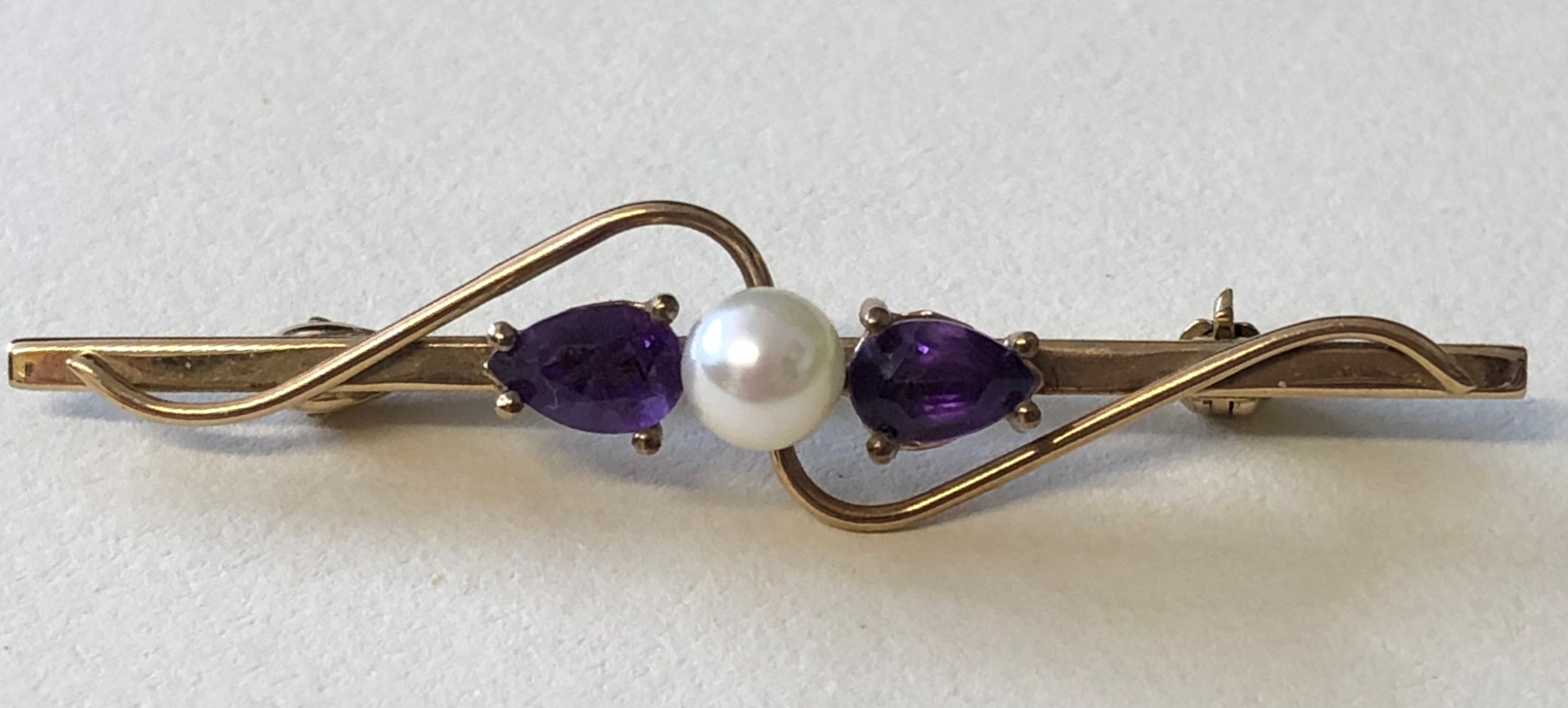 9CT YELLOW GOLD BAR BROOCH SET WITH A CULTURED PEARL FLANKED BY CLAW SET AMETHYSTS 2.